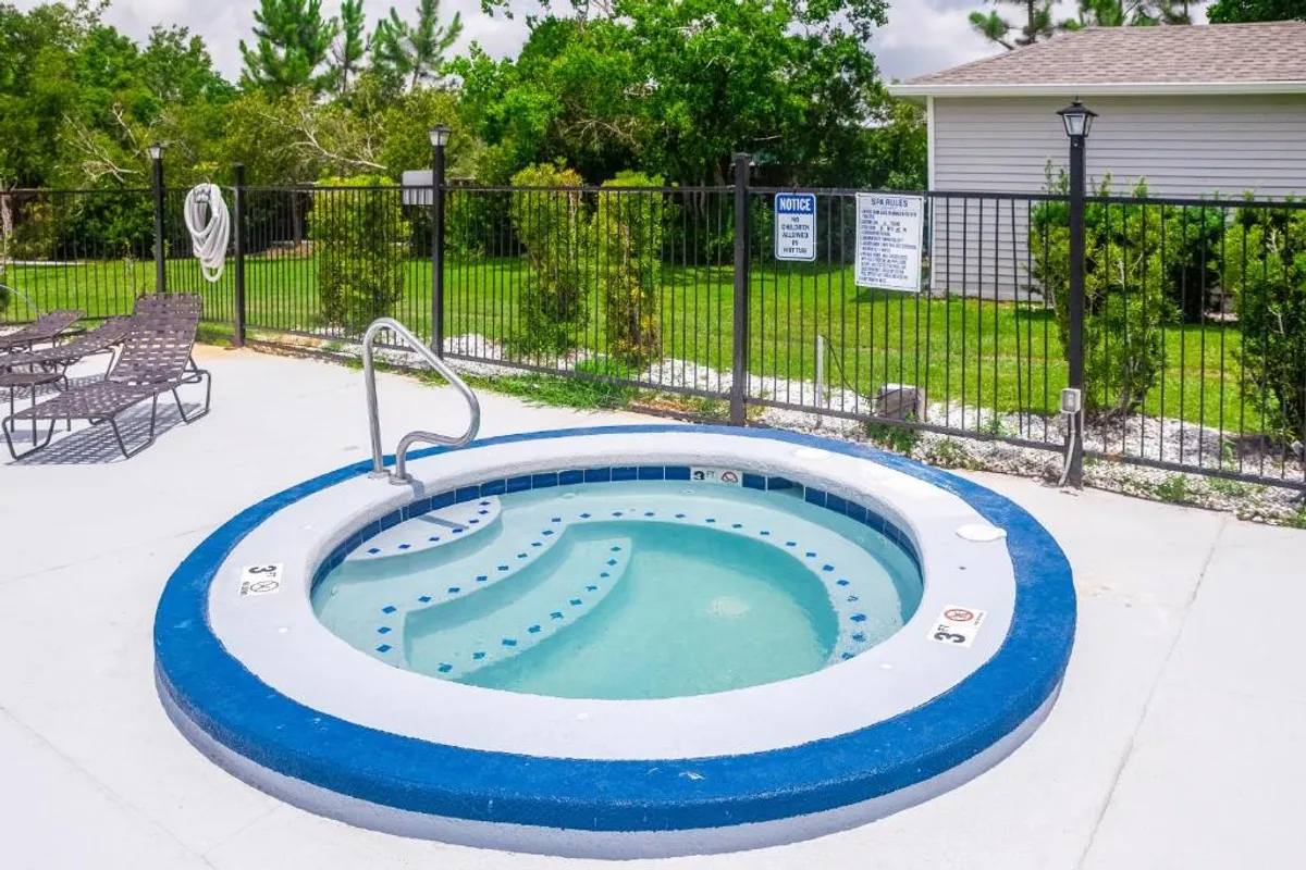 A tranquil hot tub with surrounding seating in a fenced area, inviting guests to unwind outdoors. The space is ideal for relaxing soaks after a day of exploration or socializing with fellow residents in a cozy setting.