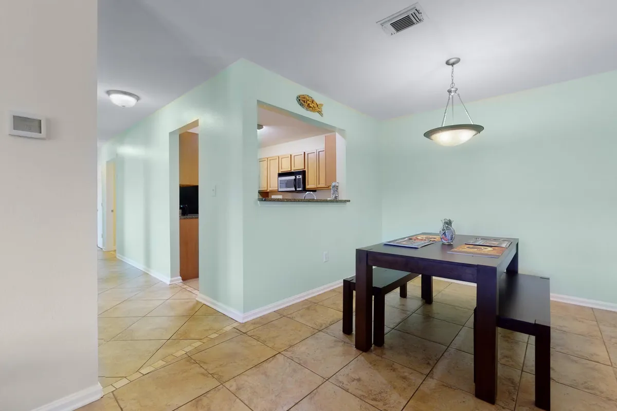 A cozy open-concept living and dining area featuring a modernized fireplace, Smart TV, a dark wood dining table with benches, and a pass-through window to the kitchen. The setup fosters easy meal service and group dining, aligning with social and shared meal experiences.