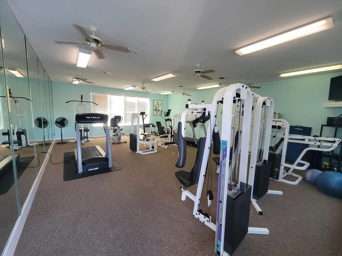 An indoor fitness center outfitted with weight machines, a treadmill, stationary bikes, and large wall mirrors. The space is well-lit and designed for cardio and strength routines, fostering an energetic, health-focused vibe for residents and guests.